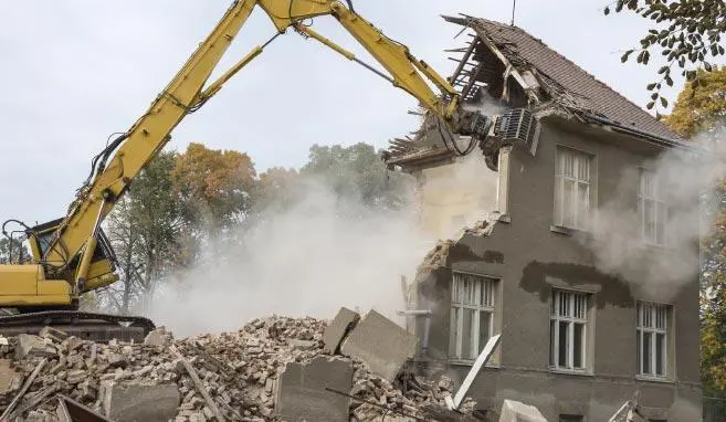 ein Bagger reißt ein Haus ab. 