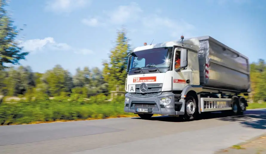 Ein TSR LKW fährt auf einer Landstraße und hat eine Mulde geladen